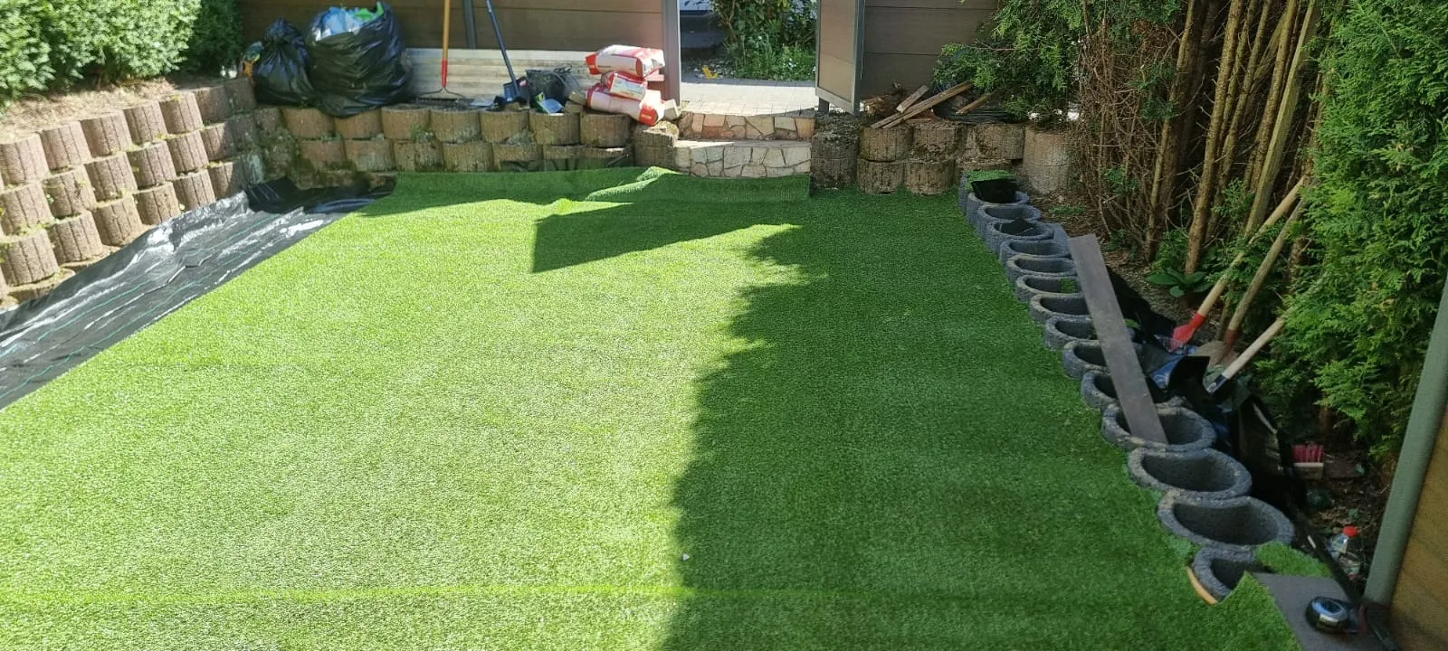 Neu angelegte Rasenfläche in einem Garten mit Hangbefestigung.