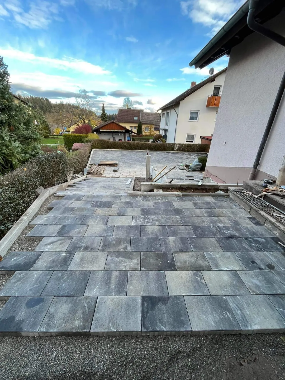 Neu verlegte graue Terrassenplatten vor einem Wohnhaus.